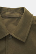 Nahaufnahme des Kragens vom Stone Island Overshirt 'Ghost Piece' oliv, Mix aus Schurwolle und Microfaser, weicher Griff, Slim Fit, Fünf-Knopf-Leiste, Umlegekragen, tonales Badge am Oberarm, Ärmelabschlüsse mit Knopf, eine Innentasche, fotografiert aus fro