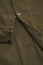 Stone Island Overshirt 'Ghost Piece' oliv, Detailaufnahme von vorne schräg oben, Mix aus Schurwolle und Microfaser, weicher Griff, Slim Fit, fünf-Knopf-Leiste, Umlegekragen, tonales Badge, Ärmel mit Knopf, Innentasche.