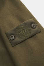 Nahaufnahme des tonalen Badges am Oberarm des Stone Island Overshirt 'Ghost Piece' oliv, aus Schurwolle und Microfaser, weicher Griff.