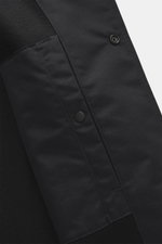 Nahaufnahme des Stone Island Overshirt 'Ghost Piece' schwarz, Slim Fit, aus Schurwolle und Microfaser mit weichem Griff, Fünf-Knopf-Leiste, Umlegekragen, tonales Badge am Oberarm, Ärmelabschlüssen mit Knopf und einer Innentasche, fotografiert von schräg o