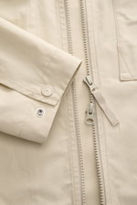 Stone Island Overshirt 'Ghost Piece' beige, Nahaufnahme von Ärmel mit Knopf, Brusttasche und robustem Zwei-Wege-Reißverschluss, glatter Baumwollcanvas.
