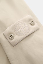 Nahaufnahme des tonalen Badges am Oberarm des Stone Island Overshirt 'Ghost Piece' beige aus Baumwollcanvas mit Knöpfen, glattem Griff.