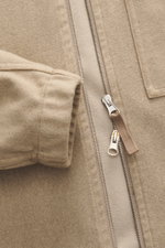 Close-up front view of Stone Island Overshirt beige showing firm, felted mix of virgin wool and microfiber, slim fit, high-closing two-way zipper, patch chest pocket with flap, typical compass badge, elastic cuffs, garment dyed, unlined.