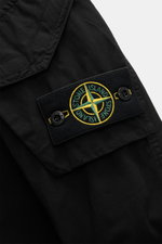 Close-up view of the sleeve of the Stone Island Overshirt 'Canvas' black, showcasing the iconic compass badge on a patch pocket with flap. Robust utility look with canvas made from pure organic cotton, durable quality, garment dyed, regular fit, robust tw