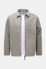 Stone Island Overshirt 'Canvas' grau, frontal fotografiert, robustes Utility-Design aus Bio-Baumwolle, Kompass-Badge am Ärmel, Regular Fit, Zwei-Wege-Reißverschluss, Umlegekragen, ungefüttert.