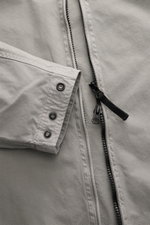Stone Island Overshirt 'Canvas' grau aus Bio-Baumwolle, Detailaufnahme von Ärmel mit Druckknöpfen und robustem Zwei-Wege-Reißverschluss.