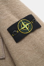 Nahaufnahme des Stone Island Overshirt beige aus Bouclé, Fokus auf das Kompass-Badge am Oberarm, leicht griffige Wolle-Microfaser.