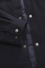 Close-up front view of Woolrich Down jacket navy melange showing wool and microfiber fabric, light down filling, snap button placket, adjustable collar with button tab, cuff sleeves with cuffs, slanted welt pockets, adjustable waist, quilted smooth lining