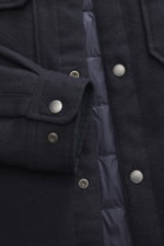 Close-up front view of Woolrich Down jacket 'Alaskan' navy melange showing wool and microfiber fabric, light down filling, slim fit, snap button placket, adjustable collar with button tab, patch chest pockets, slanted welt pockets, sleeve cuffs with cuff,