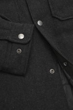 Close-up front view of Woolrich Down jacket 'Alaskan' black melange showing wool and microfiber fabric, snap button placket, patch chest pockets, sleeve cuffs with cuff, and quilted smooth lining fabric. Light down filling, slim fit, adjustable collar wit