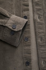 Nahaufnahme des Belstaff Overshirt 'Ravine' graubraun aus Baumwoll-Cord mit Knöpfen, Manschette und geradem Saum, seitlich fotografiert.