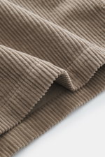 Nahaufnahme von taupefarbenem Cordstoff des Belstaff Overshirt 'Ravine', weich, mit breitem Rippenmuster, Detailansicht aus schräger Perspektive.