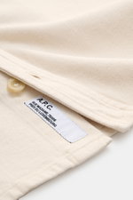Nahaufnahme von A.P.C. Overshirt sand meliert, Baumwoll-Denim, robust, garment dyed, Regular Fit, Knopf, Label, Detailansicht Kragen und Brusttasche.