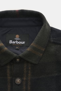 Barbour Overshirt 'Woodlane' khaki/navy kariert close-up from above showing collar, buttons, and Barbour label, soft brushed wool-mix.

<p>Kanadisches Holzfällerkaro, neu gedacht: Der gebürstete Woll-Mix fühlt sich weich an, hält angenehm warm und bleib