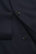 Nahaufnahme des Lardini Overshirts 'Accony' navy aus reiner Schurwolle mit Slim Fit, Vier-Knopf-Leiste und Reverskragen, schrägen Leistentaschen und Blütenanstecker, fotografiert aus schräger Perspektive.
