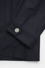 Nahaufnahme des Ace Denim Overshirt navy Ärmels mit Manschette und Metallknopf, fotografiert aus schräger Perspektive, elastische Schurwolle, leicht griffige Haptik, Slim Fit, Umlegekragen, Fünf-Knopf-Leiste, aufgesetzte Brusttaschen mit Patte, paspeliert