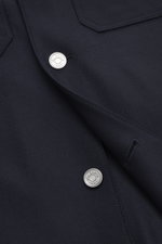 Nahaufnahme des Ace Denim Overshirt navy von schräg oben, elastische Schurwolle, Slim Fit, Umlegekragen, fünf Knöpfe, Brusttaschen mit Patte, paspelierte Fronttaschen, Ärmel mit Manschette, leicht griffige Haptik.