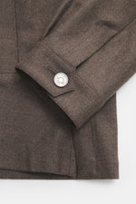 Nahaufnahme des Ärmelabschlusses vom Ace Denim Overshirt graubraun meliert aus elastischer Schurwolle mit Slim Fit, Umlegekragen, Fünf-Knopf-Leiste, aufgesetzten Brusttaschen mit Patte, paspelierten Fronttaschen und Manschetten, fotografiert von oben.
