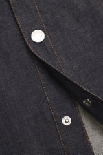 Close-up front view of the Ami Paris Denim overshirt navy showing pure cotton fabric with textured feel, heavy quality, snap button placket, turn-down collar, patch chest pocket with logo stitching, cuffed sleeve ends, oversized fit, and unlined design.