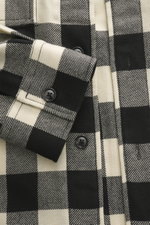 Ami Paris Overshirt black/cream checkered shown in close-up from above, highlighting snap buttons and cuff details in pure new wool, soft touch, oversized fit with adjustable collar, patch chest pockets with flap, classic sport cuff, rounded hemline, exte
