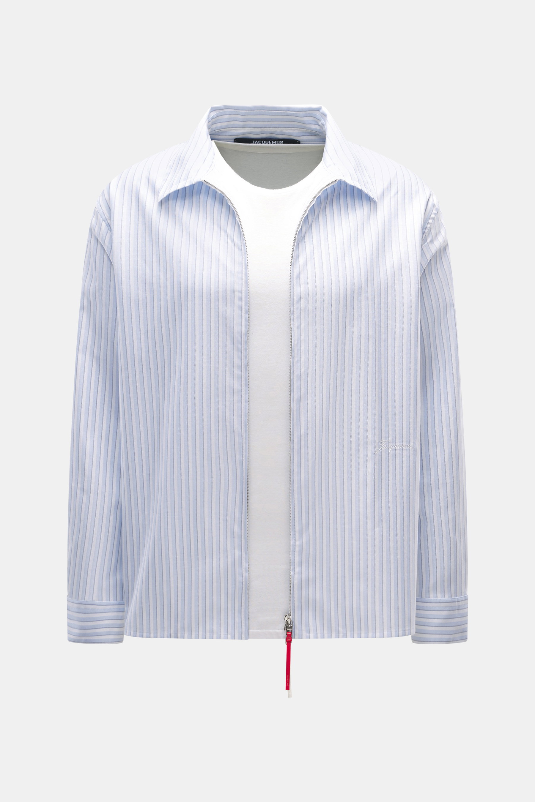 Front view of Jacquemus Light blue/white striped overshirt made of pure cotton oxford, slightly textured, oversized fit, turn-down collar, two-way zipper with decorative J-hook, classic sport cuff, and subtle logo stitching.