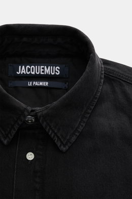 Nahaufnahme des schwarzen Jacquemus Overshirts aus Denim, reine Baumwolle, weicher Griff, Oversized Fit, Umlegekragen, glatte Knopfleiste, paspelierte Fronttaschen, Brusttasche mit Logo-Print, dekorativer J-Haken, klassische Sportmanschette, gerundeter Sa
