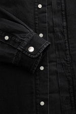 Nahaufnahme des Jacquemus Overshirt schwarz aus Denim, reiner Baumwolle, weicher Griff, Oversized Fit, Umlegekragen, glatte Knopfleiste, paspelierte Fronttaschen, Brusttasche mit Logo-Print, dekorativer J-Haken, klassische Sportmanschette, gerundeter Saum