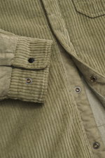 Close-up front view of the C.P. Company Cord overshirt sand, showcasing its soft cotton corduroy fabric with velvety feel, snap button placket, patch chest pocket, cuffed sleeves, and label-typical lens detail, ideal casualwear for the transitional season
