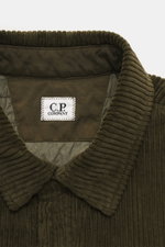 Close-up front view of the C.P. Company Corduroy Overshirt khaki collar and label showing soft cotton corduroy fabric with velvety feel, slim fit, snap button placket, turn-down collar, patch chest pocket, cuff sleeves, snap button pocket on upper arm, an