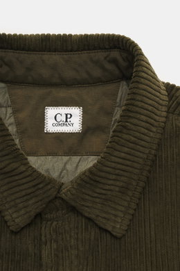 Close-up front view of the C.P. Company Corduroy Overshirt khaki collar and label showing soft cotton corduroy fabric with velvety feel, slim fit, snap button placket, turn-down collar, patch chest pocket, cuff sleeves, snap button pocket on upper arm, an