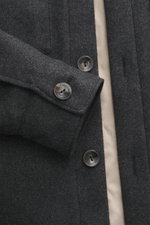 A close-up front perspective of the Agnona Cashmere overshirt dark grey melange showing pure cashmere fabric, soft touch, regular fit, six-button placket, turn-down collar, breast pockets with flap, and buttoned sleeve cuffs.