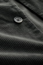 Close-up detail of a black button on the Barena Venezia Cord Overshirt dark grey, photographed from an angled top-down perspective, showing corduroy made of cotton and rayon with a soft touch, elastic quality, slim fit, five-button placket, turn-down coll