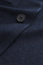 Close-up detail shot of the Harris Wharf London Cashmere overshirt navy melange showing pure cashmere fabric with knitted and felted quality, very soft touch, raw-edge finish, and a black button. The image is photographed from a top-down perspective, high