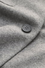 Close-up angled view of Harris Wharf London Cashmere overshirt grey melange showing pure cashmere fabric with knitted and felted quality, very soft touch, raw-edge finish, slim fit, five-button placket, turn-down collar, patch chest pockets with flap, ang
