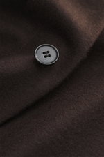 Close-up view of a dark brown button on soft, pure cashmere fabric of the Harris Wharf London Cashmere overshirt dark brown, showing knitted and felted quality with a very soft touch, photographed from above. Features include raw-edge finish, slim fit, fi