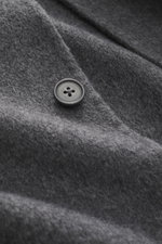 Nahaufnahme aus schräger Perspektive eines Knopfes am Officine Générale Overshirt 'Hayri' dunkelgrau, reine Wolle, weicher Griff, Regular Fit, Vier-Knopf-Leiste, fallendes Revers, aufgesetzte Fronttaschen, Unconstructed-Design.