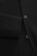 Nahaufnahme aus schräger Perspektive eines schwarzen Officine Générale Overshirt 'Simao' mit reiner Wolle, weichem Griff, Regular Fit, Fünf-Knopf-Leiste, Stehkragen, aufgesetzten Fronttaschen und Unconstructed-Design.