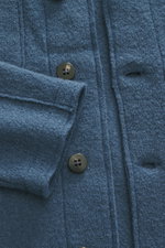 Nahaufnahme des graublauen 04651/ A trip in a bag Woll-Overshirt 'Boiled' aus Bouclé-Strick, Slim Fit, Raw-Edge-Finish, Schalkragen, Vier-Knopf-Leiste, aufgesetzter Brusttasche, kurzen Saumschlitzen und weichem Griff, gewalkte Qualität, fotografiert aus F