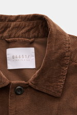 Nahaufnahme des Umlegekragens von 04651/ A trip in a bag Cord-Overshirt braun aus Baumwollcord, Slim Fit, mit softerm Griff, Fünf-Knopf-Leiste, Taschen und klassischer Sportmanschette, leicht elastische Qualität, fotografiert von oben.