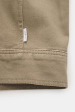Nahaufnahme der Gewebestruktur und Nahtdetails des taupefarbenen 04651/ A trip in a bag Overshirt 'Workwear Jacket' aus reiner Baumwolle, Slim Fit, leicht griffig, Fünf-Knopf-Leiste, Umlegekragen, aufgesetzte Brusttaschen, Unconstructed Design, Seitenansi