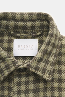 Nahaufnahme des Kragens und Labels des 04651/ A trip in a bag Overshirt 'Workwear Jacket' oliv/dark olive kariert, Baumwoll-Microfaser-Mix, weicher Griff, Karo-Webmuster.