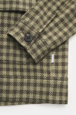 Nahaufnahme des Ärmelabschlusses mit Manschette und Knopf des oliv/dark olive karierten 04651/ A trip in a bag Overshirt 'Workwear Jacket' aus Baumwoll-Microfaser-Mix mit weichem Griff, Regular Fit, Karo-Webmuster und kleinem Weblabel, fotografiert von ob