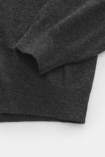 Close-up of the Aida Barni Cashmere V-neck jumper dark grey melange sleeve and hem, photographed from above, showing fine knit, ribbed cuffs, and soft cashmere texture.