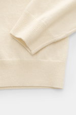 Close-up from above of the Aida Barni Cashmere V-neck jumper cream sleeve and hem, showcasing pure cashmere, soft feel, fine knit, ribbed cuffs, and regular fit.