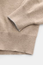 Nahaufnahme des Ärmelbündchens mit schmaler Kontrastkante des beigefarbenen Brunello Cucinelli Cashmere V-Neck Pullovers aus feinem, weichem Strick.