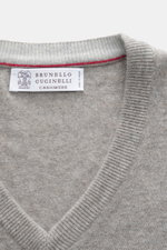 Nahaufnahme des V-Ausschnitts vom Brunello Cucinelli Cashmere V-Neck Pullover taupe meliert mit feinem Strickbild und schmalen Kontrastkanten, fotografiert von oben.