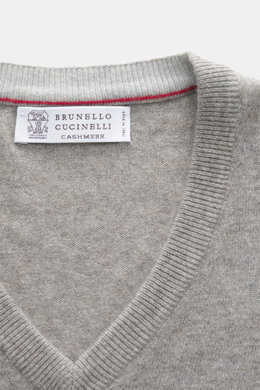 Nahaufnahme des V-Ausschnitts vom Brunello Cucinelli Cashmere V-Neck Pullover taupe meliert mit feinem Strickbild und schmalen Kontrastkanten, fotografiert von oben.