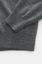 Nahaufnahme des FTC Cashmere V-Neck Pullover dunkelgrau meliert, fotografiert von oben, zeigt feines Strickbild, Slim Fit, V-Ausschnitt und komfortable Rippbündchen aus nachhaltigem Fair-Trade-Cashmere.