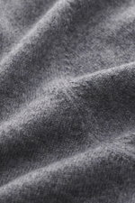 Nahaufnahme des fein gestrickten, dunkelgrau melierten BRAUN Hamburg Cashmere V-Neck Pullovers, reiner Cashmere, sehr weicher Griff, Slim Fit, V-Ausschnitt, flexible Rippbündchen, Made in Italy, aus schräger Perspektive.