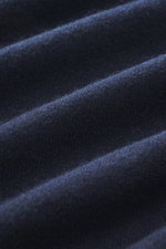 Nahaufnahme des feinen Strickbilds eines navyfarbenen BRAUN Hamburg Cashmere V-Neck Pullovers, reiner Cashmere, sehr weicher Griff, Slim Fit, V-Ausschnitt, flexible Rippbündchen, Made in Italy, fotografiert aus der Detailperspektive.